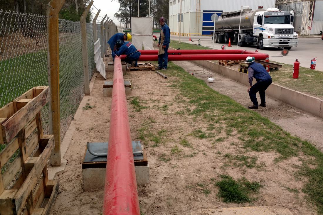 Tendido de cañería de red de incendio sobre soportes, con el equipo en obra y extintores de cobertura.