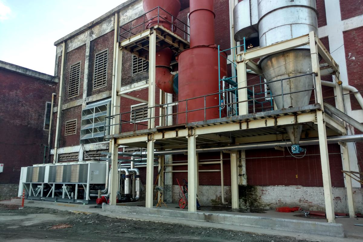 Planta de proceso con torres, ciclones y estructura de servicios.
